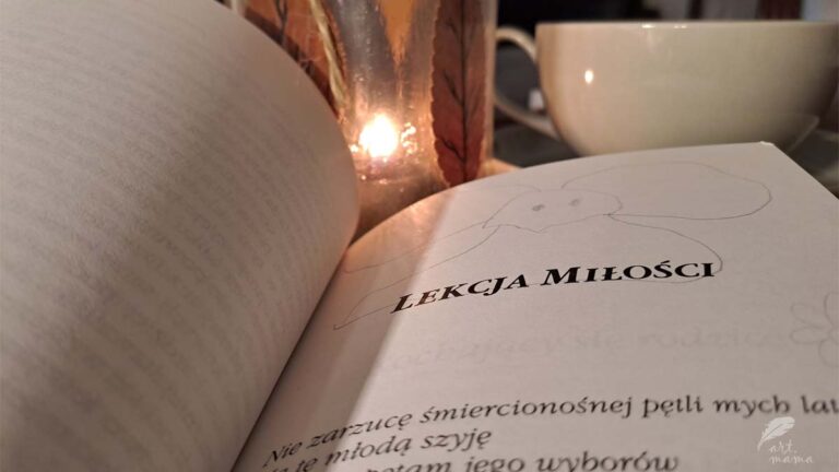 Książka otwarta na rozdziale zatytułowanym "Lekcja miłości. obok książki lampion ze świeczką i szara filizanka