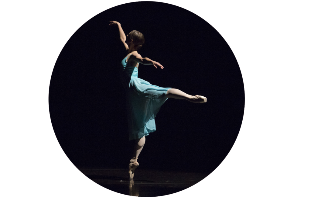 Tancerka baletowa na scenie, w niebieskiej zwiewnej sukience tańcząca na czubkach palców